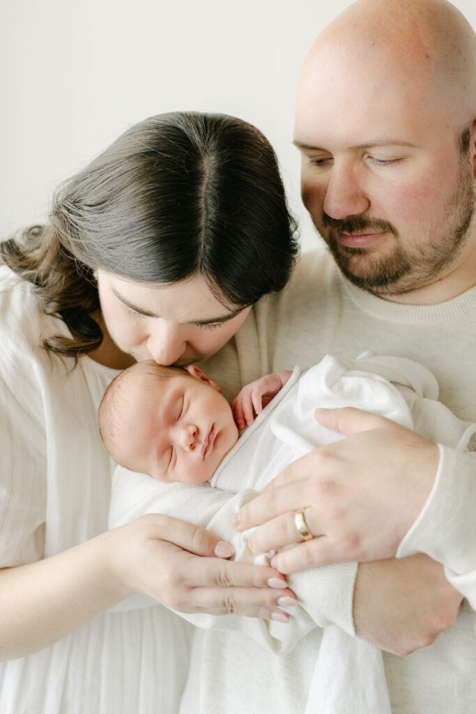 Mom kissing newborn baby girl with dad.